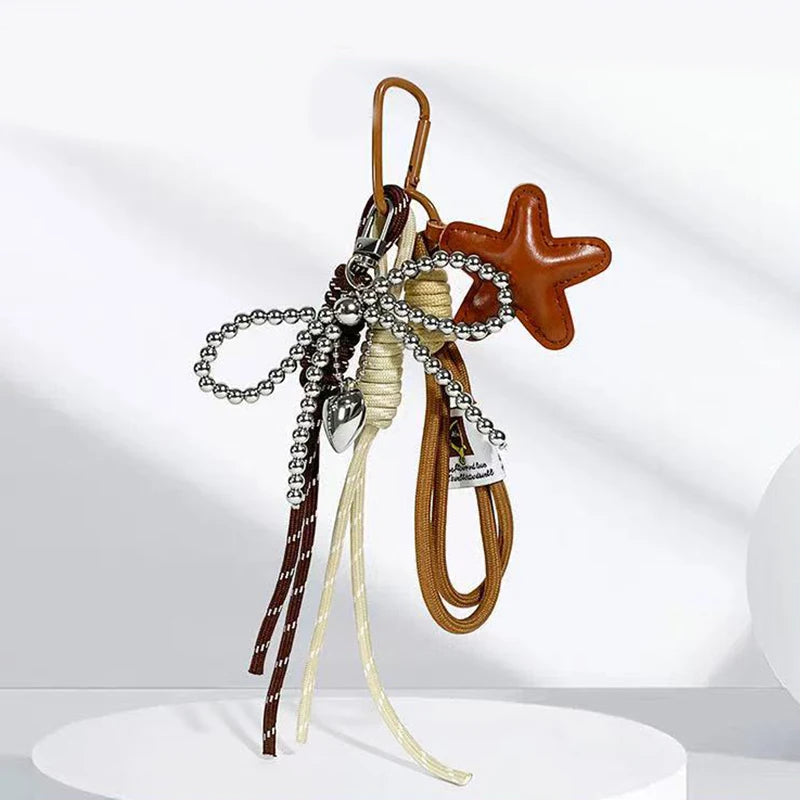 A brown leather bowknot star keychain charm with silver chains and leather accents.