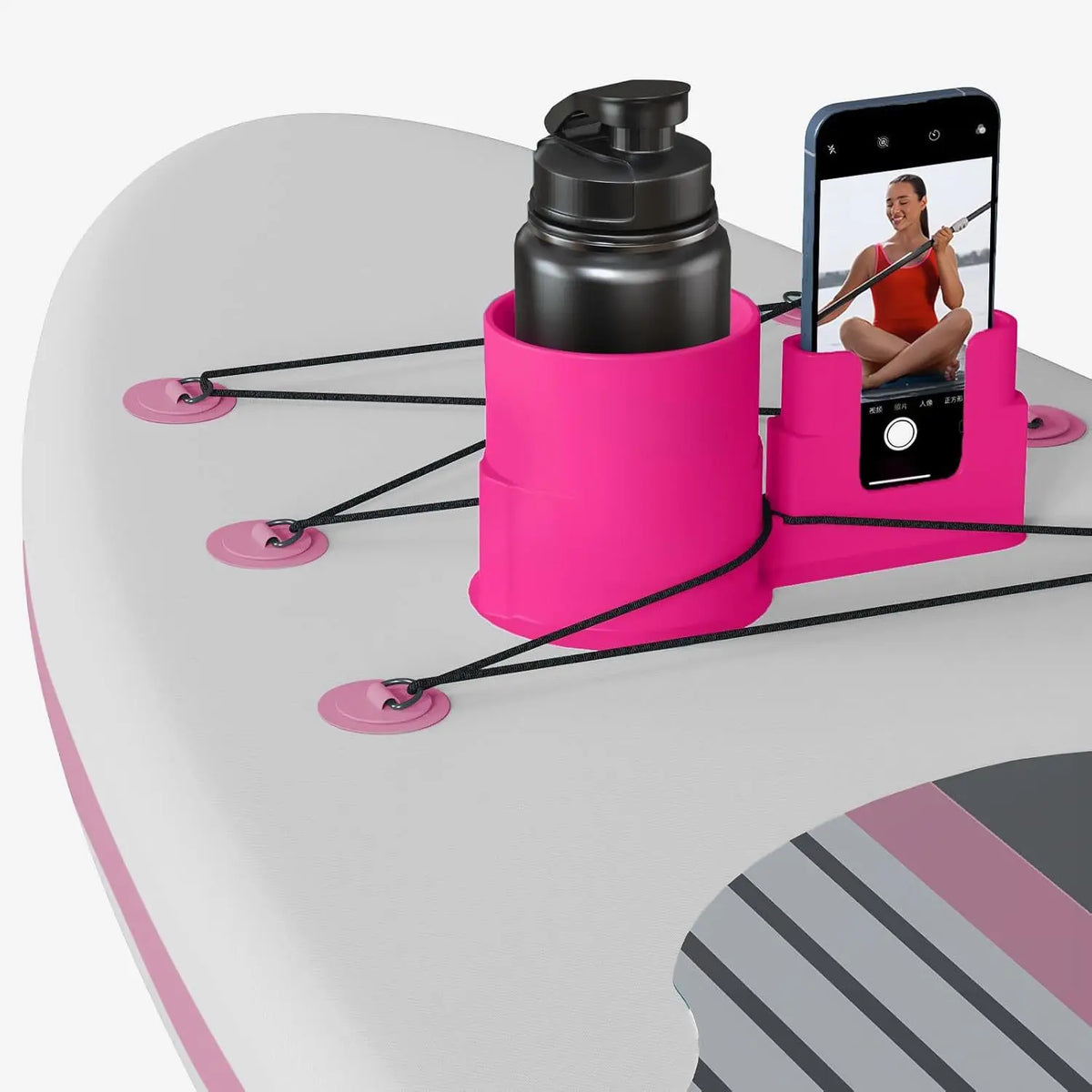 A pink multi-functional kayak drink holder and phone stand with a black bottle and a smartphone displayed.