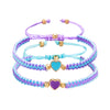 Three layered friendship bracelets featuring purple, blue, and lavender beads with gold accents.