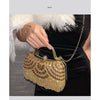A close-up of an elegant diamond rhinestone evening clutch bag with a golden tassel being held against a black background.