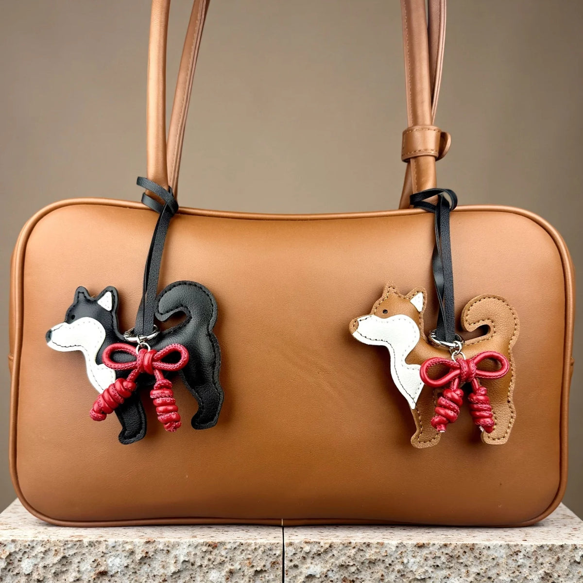 Bolso de cuero marrón con un dije de perro Shiba Inu blanco y negro y un lazo de cuero rojo trenzado a mano.