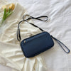 A navy blue multi-functional passport and document organizer bag resting on a white draped fabric with yellow tulips.