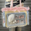 A transparent shoulder tote bag with a light yellow body, pink ribbon trim, and clear plastic pockets.