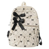 A cream-colored corduroy backpack with a black bow print design.