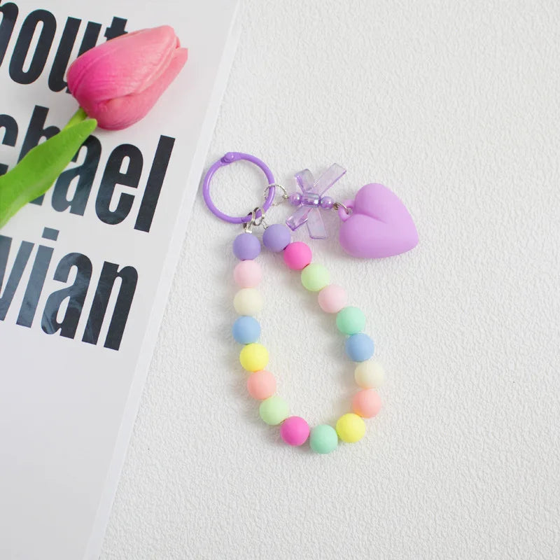 A colorful bead keychain featuring a heart charm and an O-ring clip, with beads in shades of pink, purple, blue, and yellow.