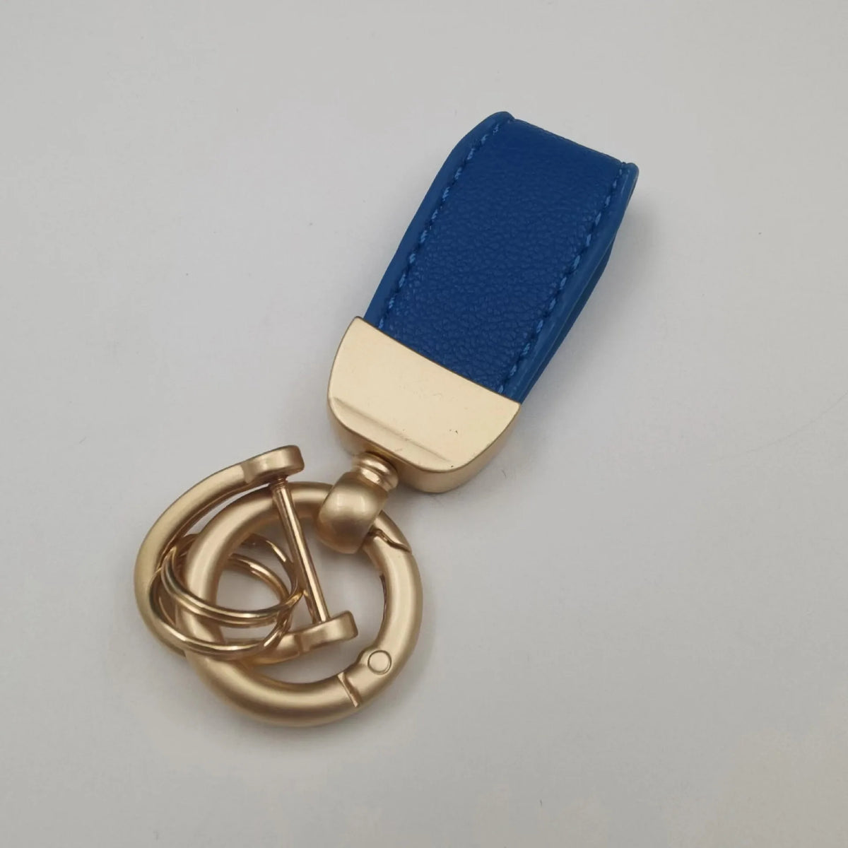 Goldfarbener Leder-Schafsfell-Auto-Schlüsselanhänger mit dunkelblauer Stoffriemen.