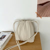 A beige PU leather pleated crossbody bag resting on a wooden surface.