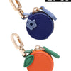 Two coin purse keychains featuring a blue star and an orange cherry fruit shape.
