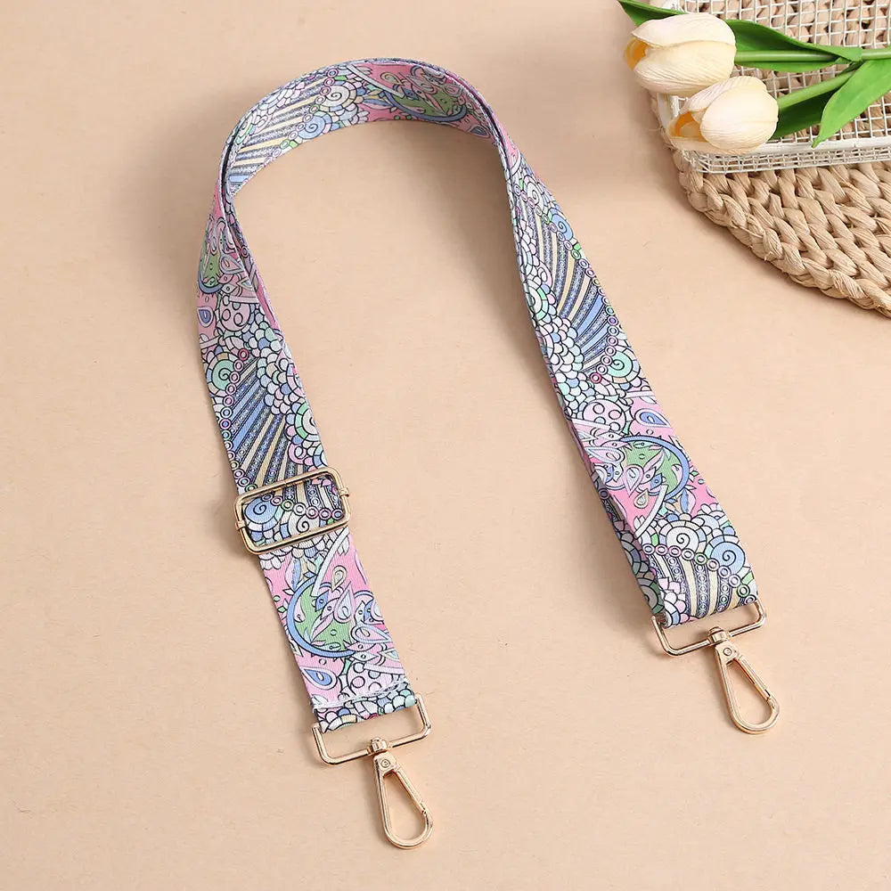 A patterned nylon crossbody bag strap with a metal buckle is displayed on a beige background.