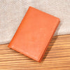 A genuine leather brown bifold card holder resting on a wooden surface.