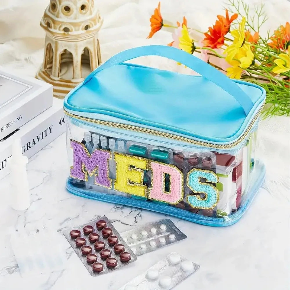A clear embroidered toiletry bag filled with various colored pills and capsules on a white marble surface.