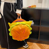 A person holds a bright orange and yellow novelty backpack shaped like a cheeseburger.