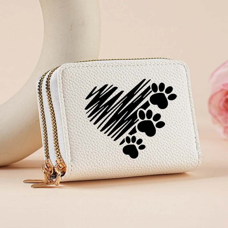 A white heart-shaped zipper wallet featuring a black paw print design, shown against a light background.