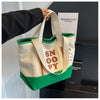 A canvas shoulder bag featuring Snoopy cartoon design in white, beige, and green colors.