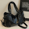 A black vintage style leather tote bag with a crossbody strap is displayed on a white surface.