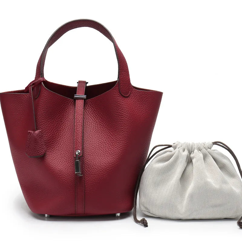 Tiefburgunder rotes Echtes Leder-Bucketbag mit Henkel und passender hellgrauer Schnurtasche.