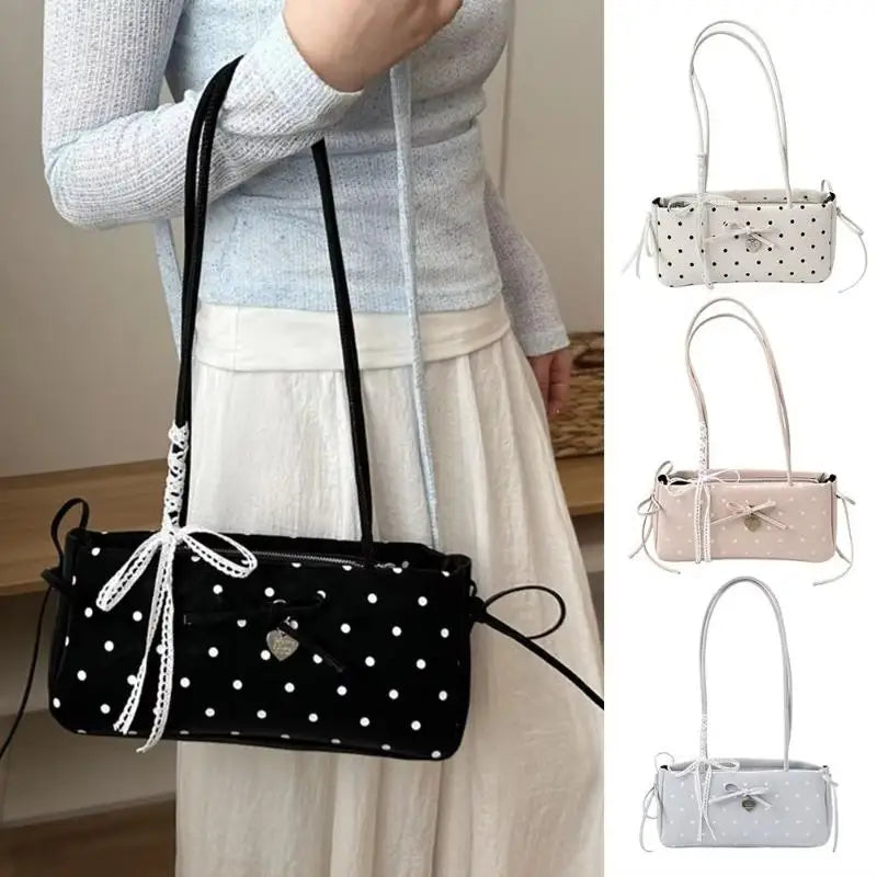 Schwarze Polka-Dot-Shoulderbag mit weißer Spitze vor einem hellen Rock.