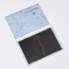 A light blue passport card holder with a marbled texture and a dark cover inside.