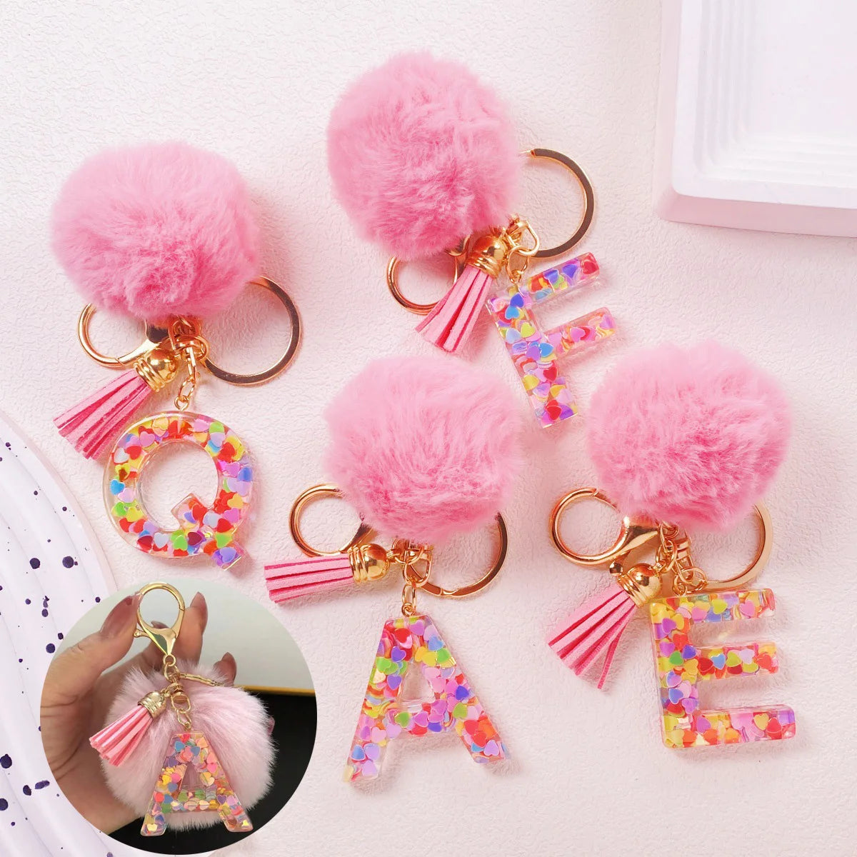 Pink fuzzy pom-pom initial letter keychains in shiny resin for bags and backpacks