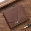 A brown men's slim leather bi-fold wallet resting on a wooden surface next to a gold pen.