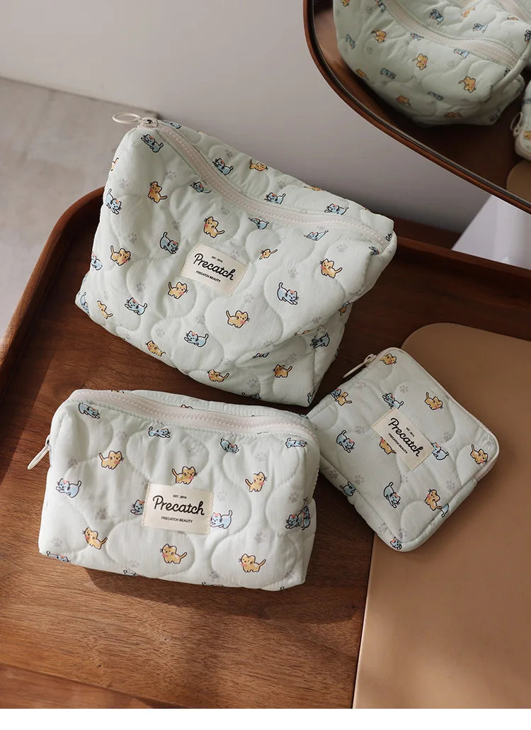White quilted cosmetic storage pouches with a light blue cat print featuring small yellow cats.