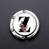 Silver foldable letter hanger hook with a floral design on a dark gray background