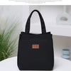 A black durable aluminum foil insulated lunch bag with a woven logo sits on a white surface.