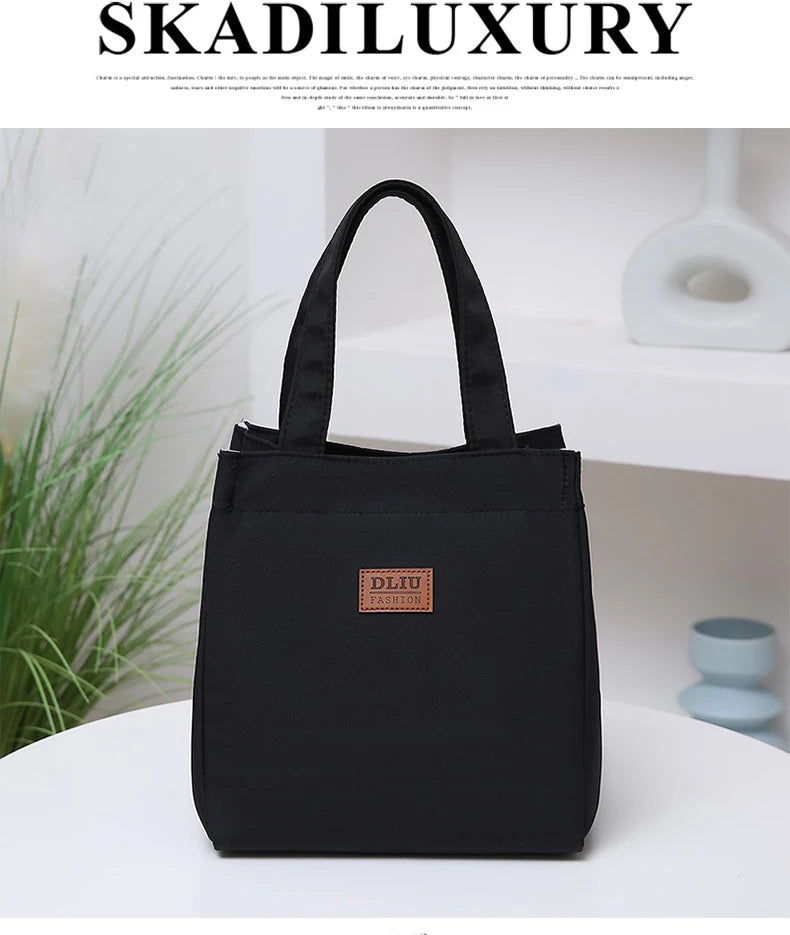 A black durable aluminum foil insulated lunch bag with a woven logo sits on a white surface.