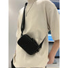 A beige t-shirt is worn by a person, featuring a black PU leather shoulder bag with a silver chain.