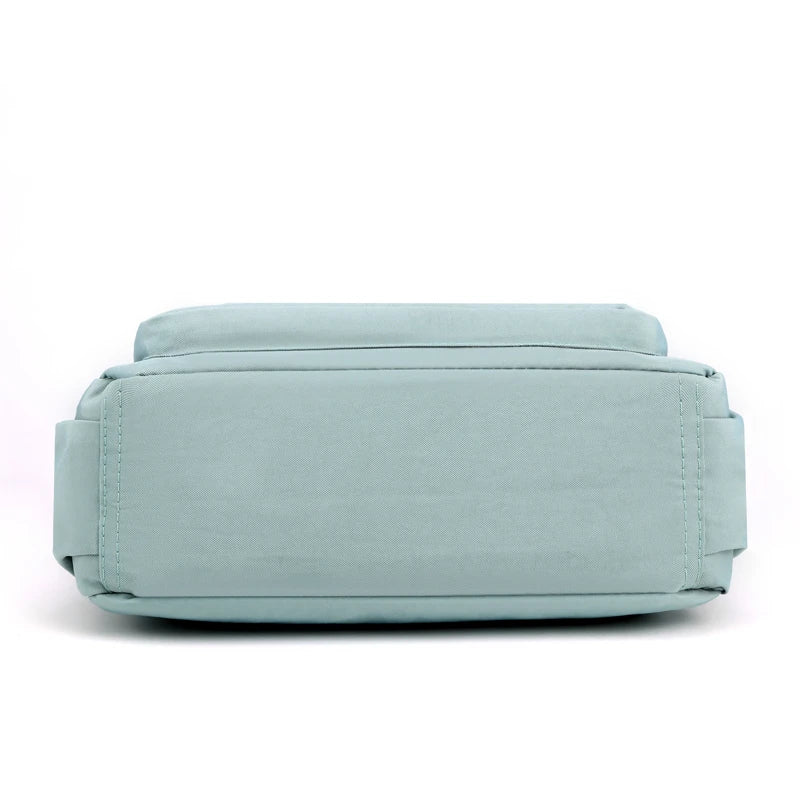 A light blue waterproof nylon crossbody shoulder bag lying flat.