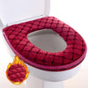 A deep red plush waterproof toilet seat cover is shown placed on a white toilet bowl.