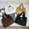 A collection of four foldable mini keychain tote bags in white, beige, brown, and black fabric.