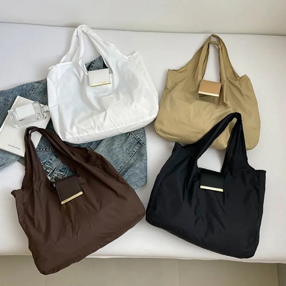 A collection of four foldable mini keychain tote bags in white, beige, brown, and black fabric.