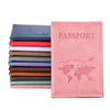 A pink leather passport holder with a world map design and a stack of colored cardholders.