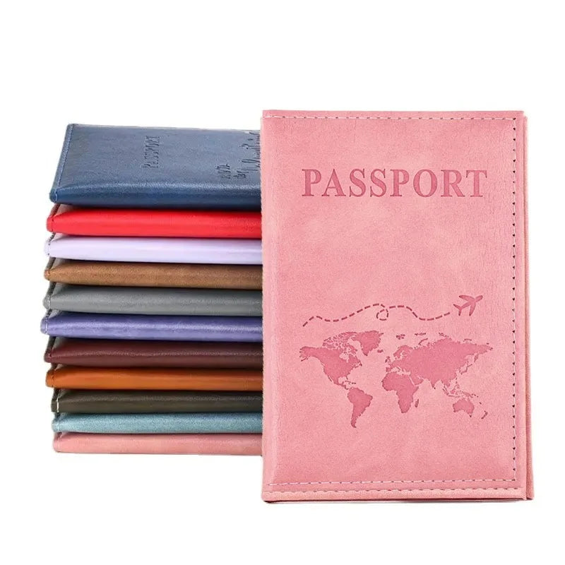 A pink leather passport holder with a world map design and a stack of colored cardholders.