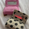 A pink striped makeup bag with a flip-top mirror is shown open on a white surface.