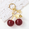 Gold-toned keychain featuring a red crystal cherry fruit charm on a white background.