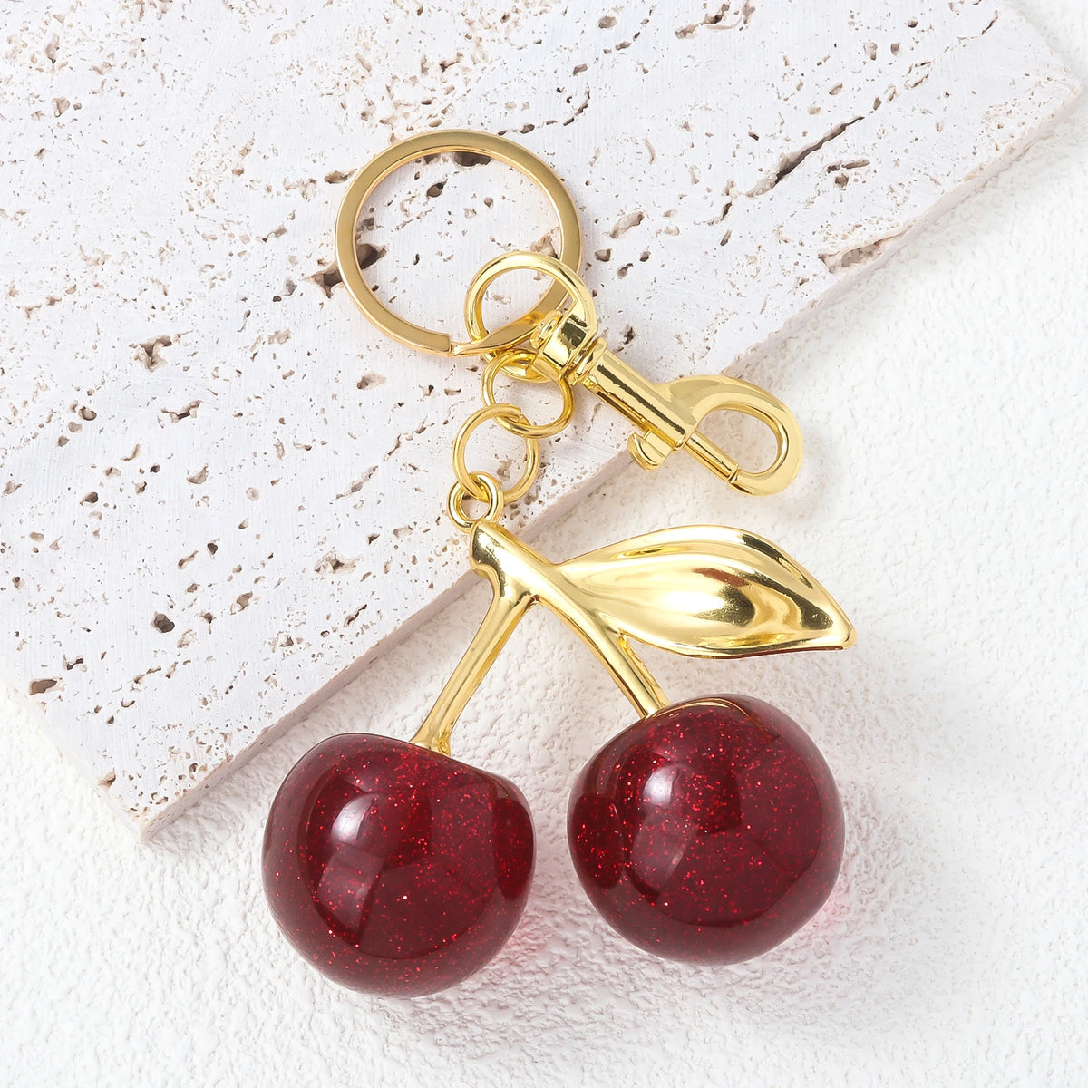Gold-toned keychain featuring a red crystal cherry fruit charm on a white background.