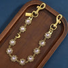 Gold-toned crystal petal keychain with rhinestone charms displayed on a wooden tray.