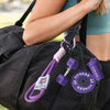 A hand is holding a black gym bag with purple fitness keychain charms attached to the strap.
