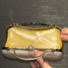 A hand holds an elegant gold and silver clutch bag decorated with diamond rhinestones and a golden tassel.