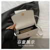 A white shoulder messenger bag is shown open inside a dark gray fabric, revealing a gold-toned wallet.