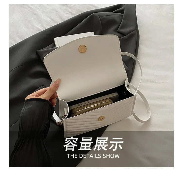 A white shoulder messenger bag is shown open inside a dark gray fabric, revealing a gold-toned wallet.