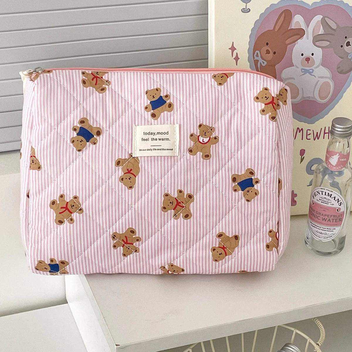 A pink and white striped cosmetic makeup bag featuring a pattern of small brown bear illustrations.