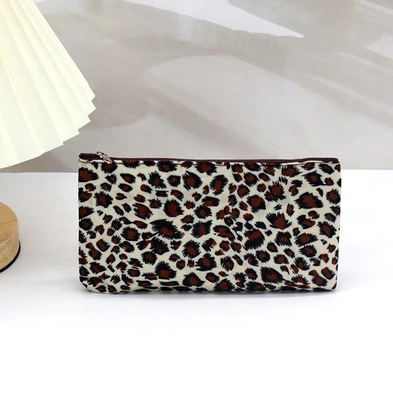 A brown and black leopard print zippered cosmetic bag resting on a white surface.