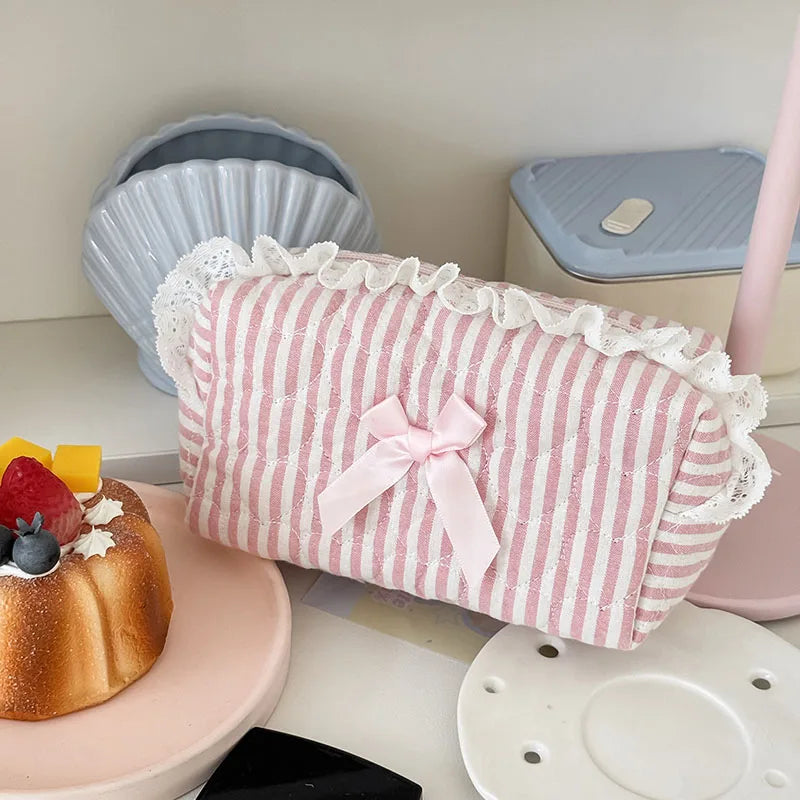 Pink rose sweetheart cosmetic storage pouch with white lace trim resting on a pink surface.