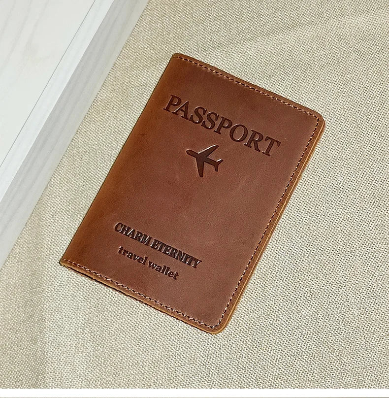 A brown genuine leather passport holder with a stitched edge and embossed text on a beige fabric background.
