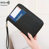 A black passport wallet with a blue accent and wrist strap is shown being held by a hand.
