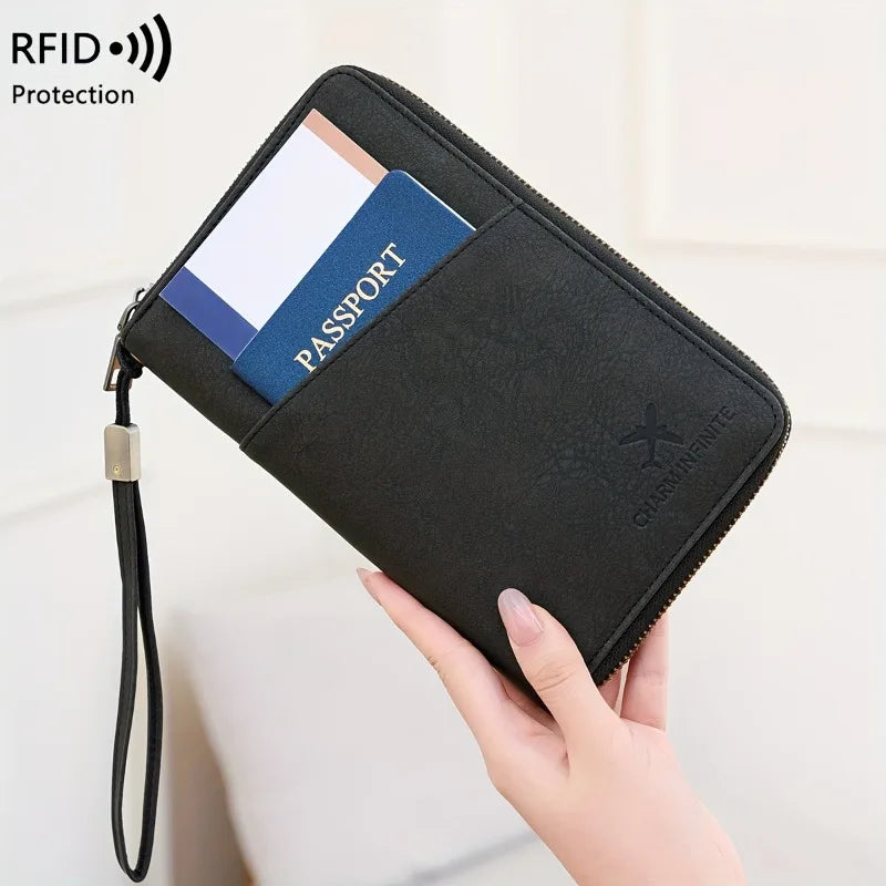 A black passport wallet with a blue accent and wrist strap is shown being held by a hand.