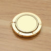 A round, gold-colored metal object with a central opening and four small loops for hanging.